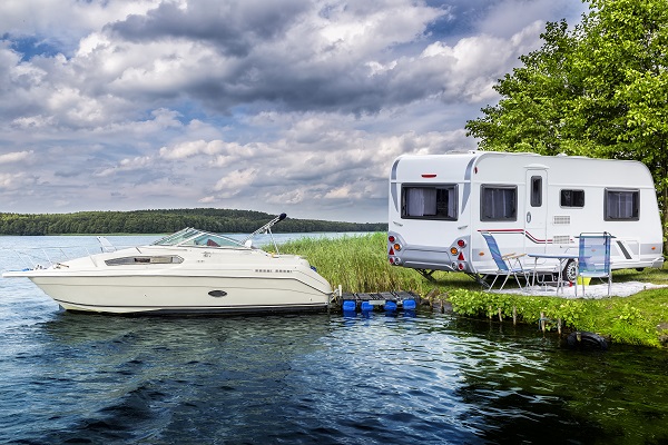 Boat and recreational vehicle on lake and shore.